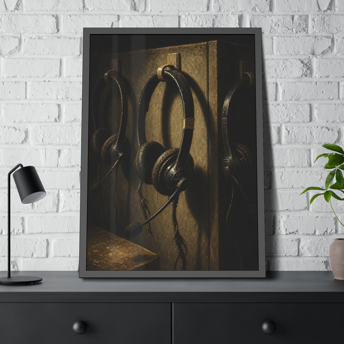 Three worn call center headsets hanging on wall hooks in dim light. The Headsets Left Hanging by Garabaggio, framed fine art print hanging in a room.
