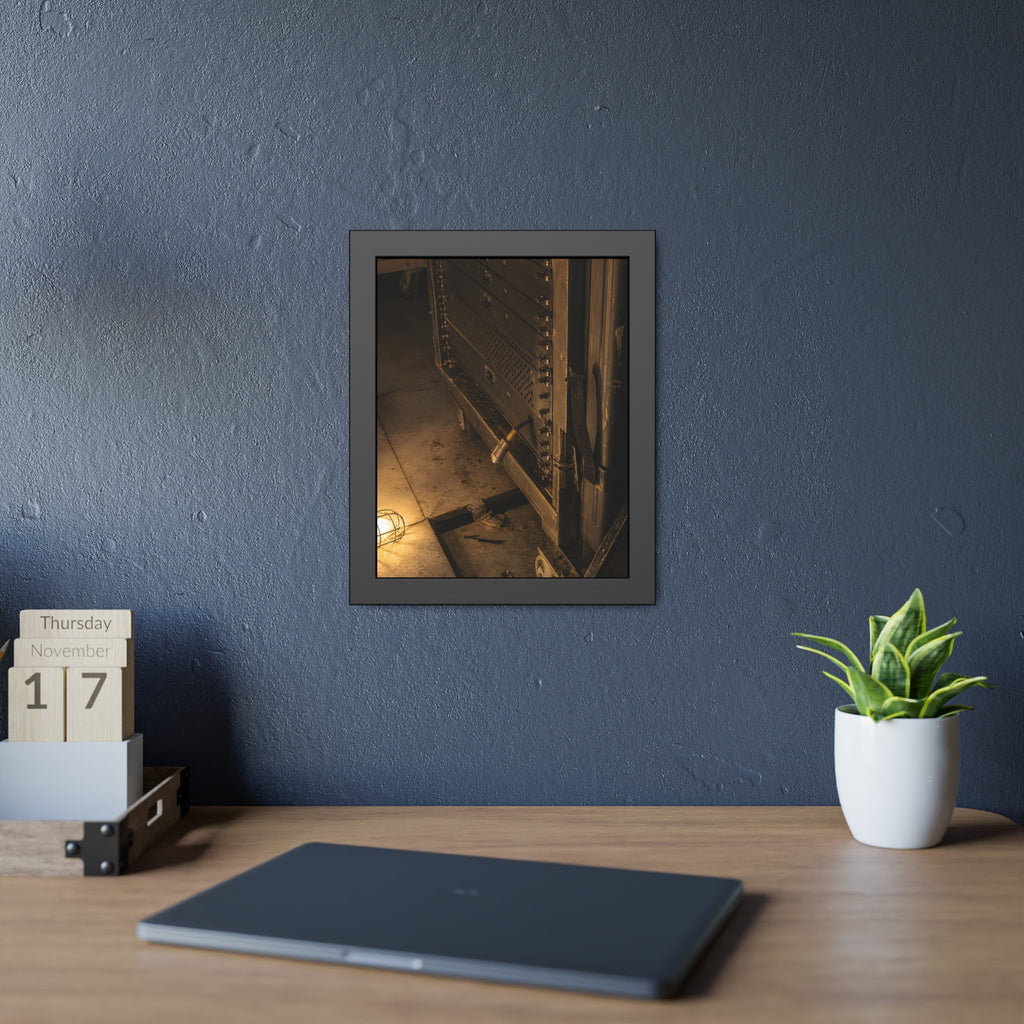 A server rack on a concrete floor beside a caged work light. The Silence at Cutover by Garabaggio, framed fine art print hanging in a room.