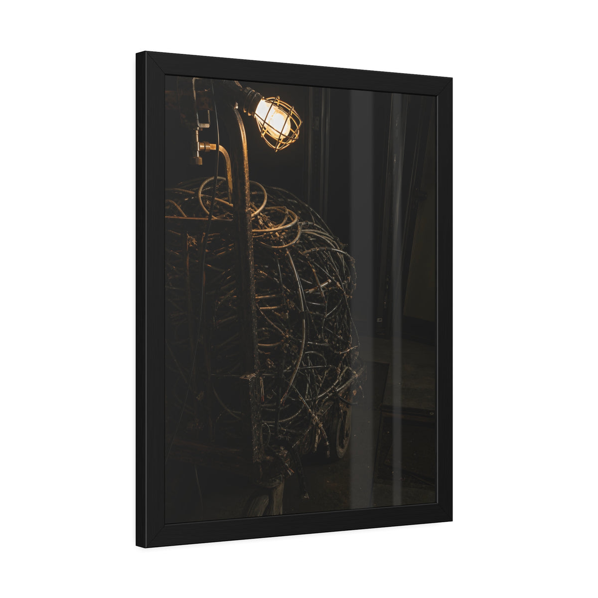 A tangled ball of cables on a hand cart under a caged work lamp. The Cable Harvest by Garabaggio, framed fine art print hanging in a room.