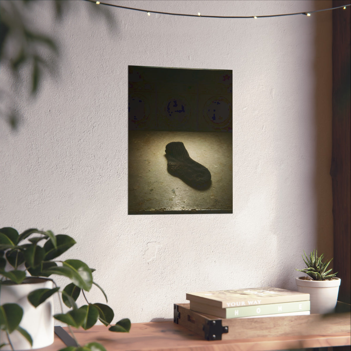 A single dark sock on a laundromat floor before dim washing machines. The Orphaned Sock by Garabaggio, fine art print hanging in a room.