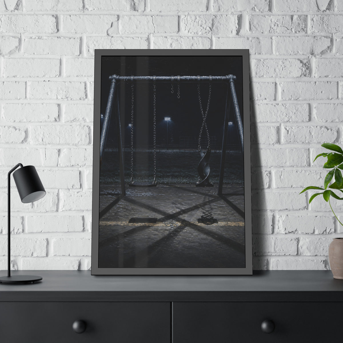 An empty swing set at night with one seat twisted up on its chains. The First Hour: The Twisted Seat by Garabaggio, framed fine art print hanging in a room.