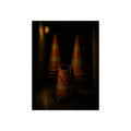 Stacked traffic cones behind a crushed one under a caged wall lamp. The Multiplication of Cones by Garabaggio, fine art print, 12″ x 16″.