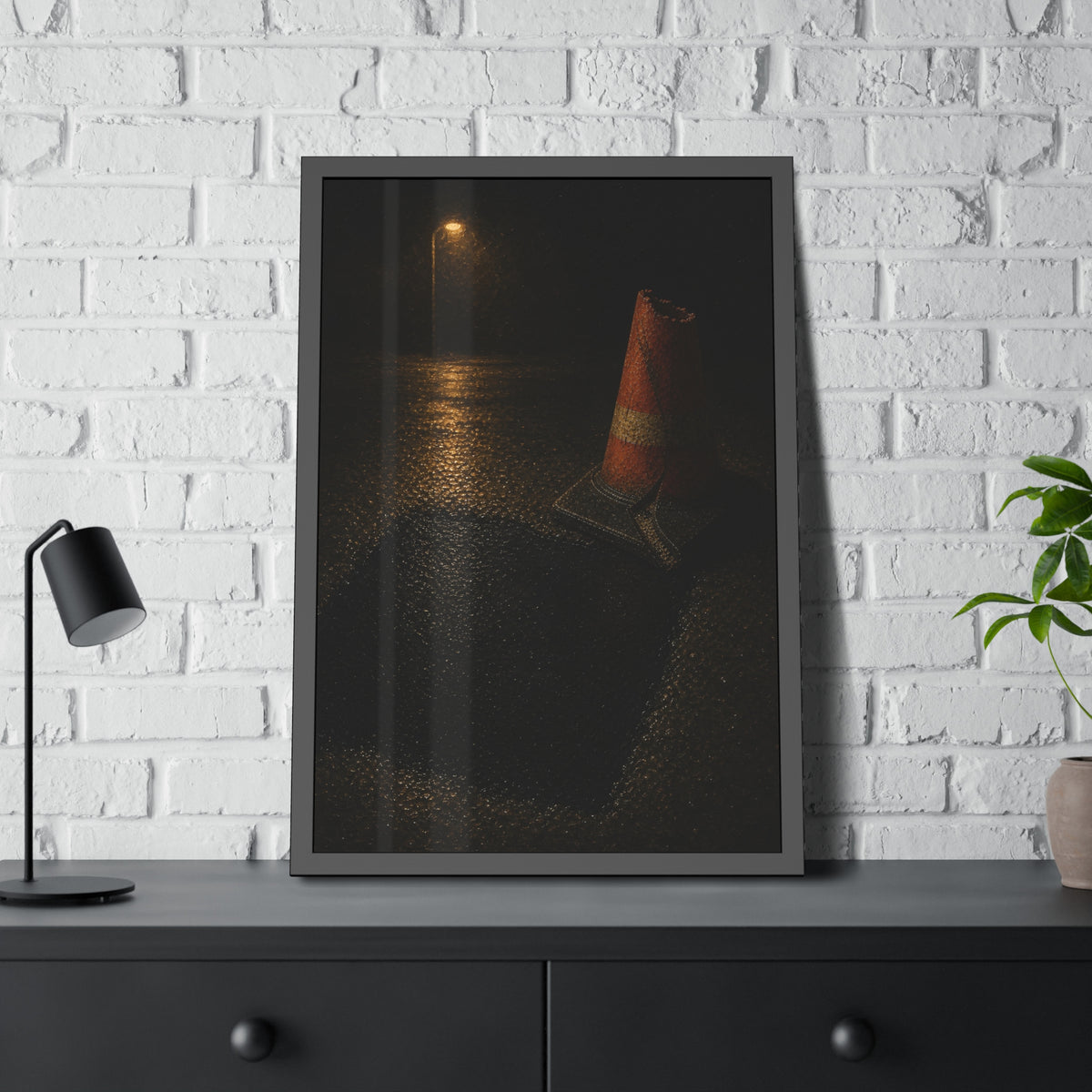 A traffic cone beside a fresh asphalt patch under a street lamp. The Sentinel After Repair by Garabaggio, framed fine art print hanging in a room.