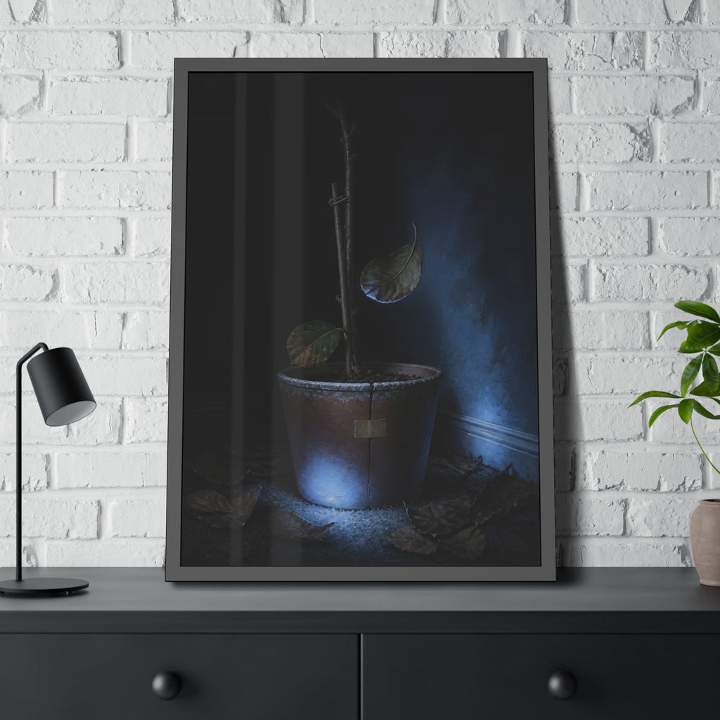 A bare potted plant dropping a leaf, dead leaves on the floor. The Leaf Lets Go by Garabaggio, framed fine art print hanging in a room.