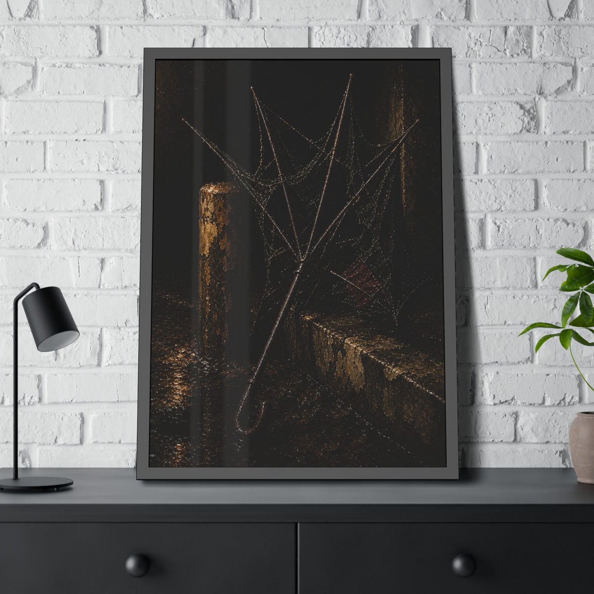 A broken umbrella with torn fabric leaning against a post on a wet curb. The Crown of Ribs by Garabaggio, framed fine art print hanging in a room.