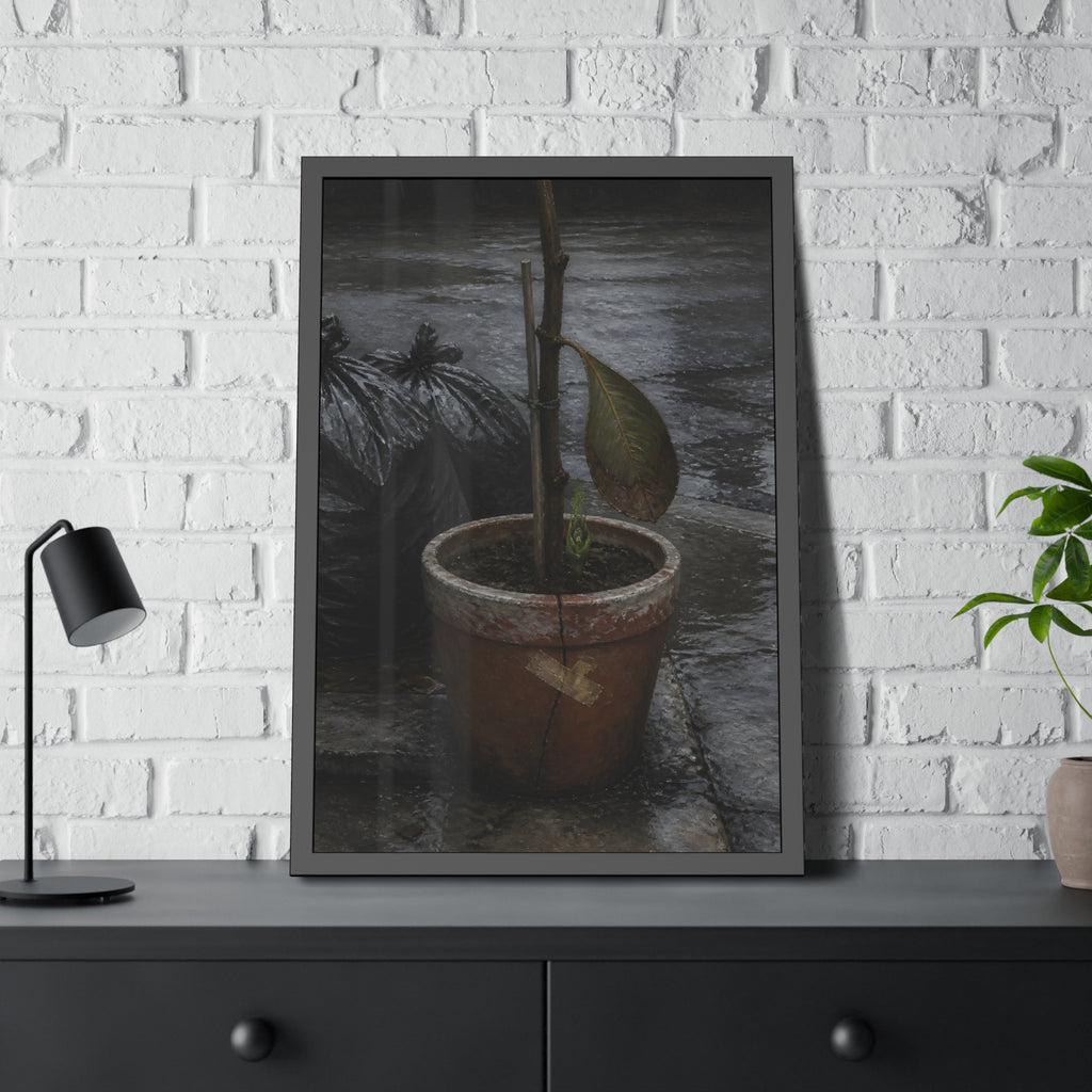 A taped clay pot with one leaf and a green shoot on wet pavement. The Green at the Base by Garabaggio, framed fine art print hanging in a room.