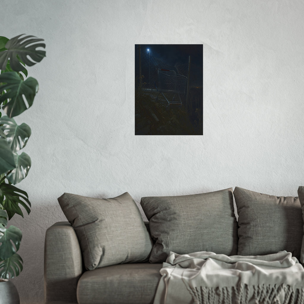 A shopping cart wedged in a chain link fence under a streetlamp. The Abandonment at the Ravine Fence by Garabaggio, fine art print hanging in a room.