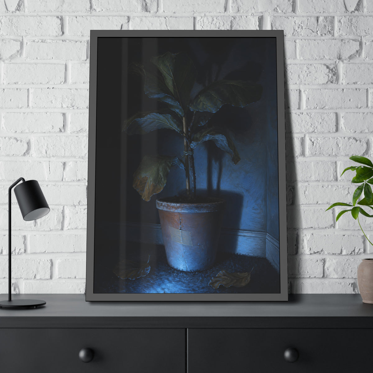 A dying potted plant in a corner washed in blue television light. The Television Hours by Garabaggio, framed fine art print hanging in a room.