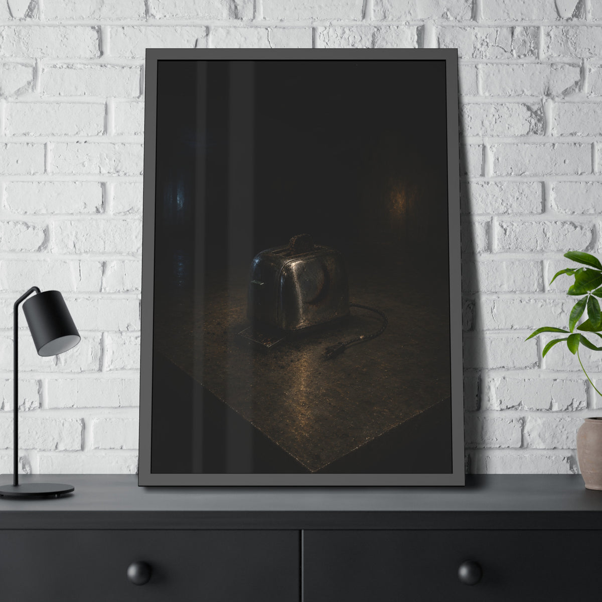 A scorched chrome toaster alone on a metal counter in a dark room. The Cooling on Steel by Garabaggio, framed fine art print hanging in a room.