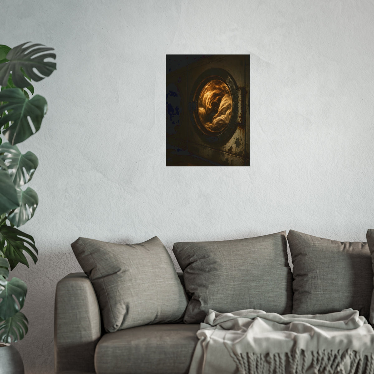 A washer drum tumbling laundry lit amber behind its glass door. The First Spin by Garabaggio, fine art print hanging in a room.