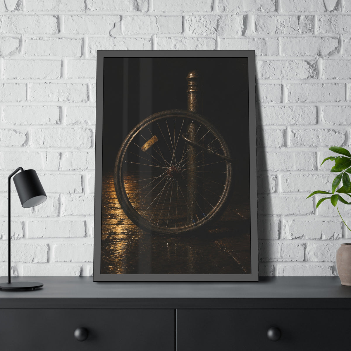 A bare bicycle wheel locked to a post on wet pavement. The Wheel Without a Bicycle by Garabaggio, framed fine art print hanging in a room.