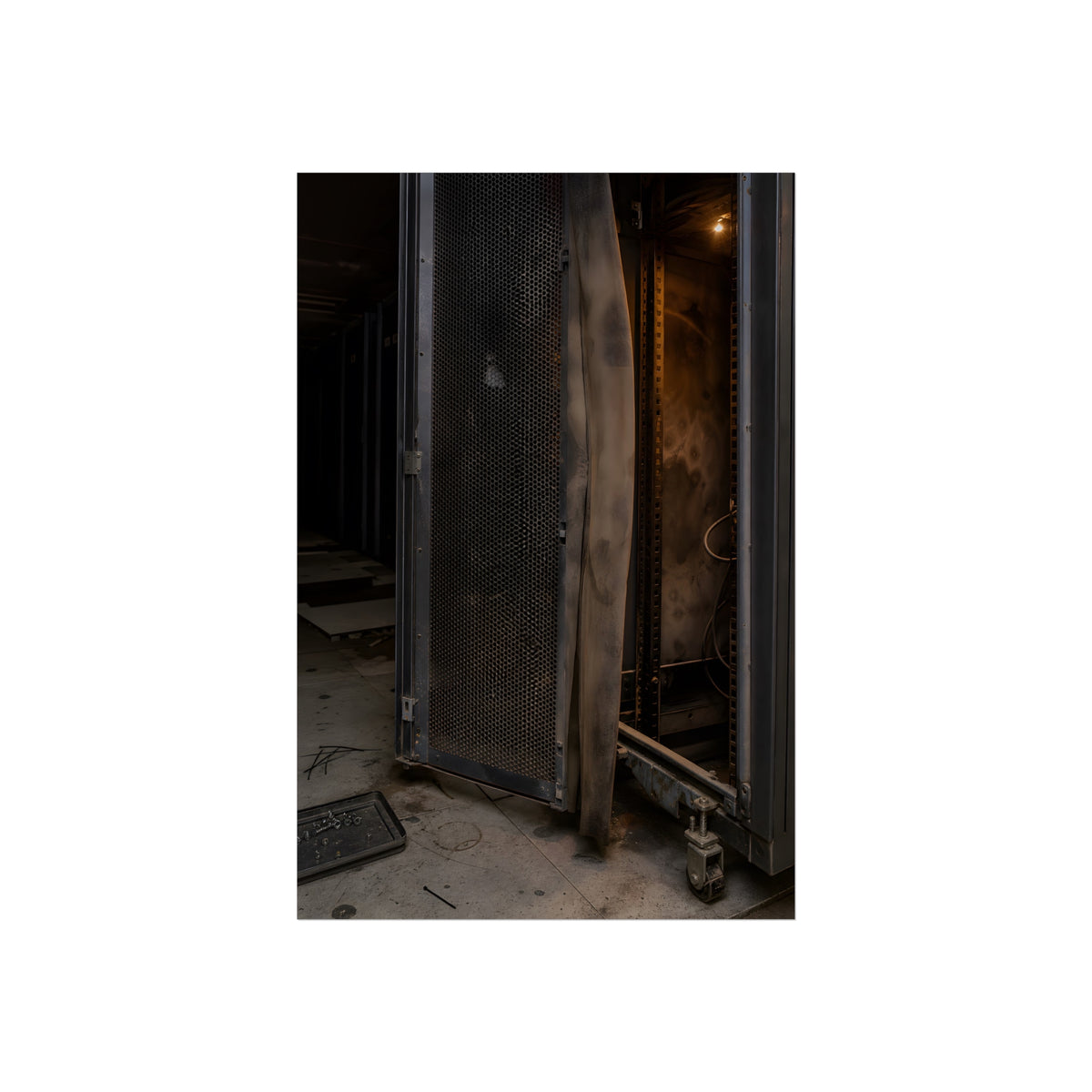 An open server rack cabinet with a mesh door and warm glow inside. The Heat Behind the Doors by Garabaggio, fine art print, 24″ x 36″.