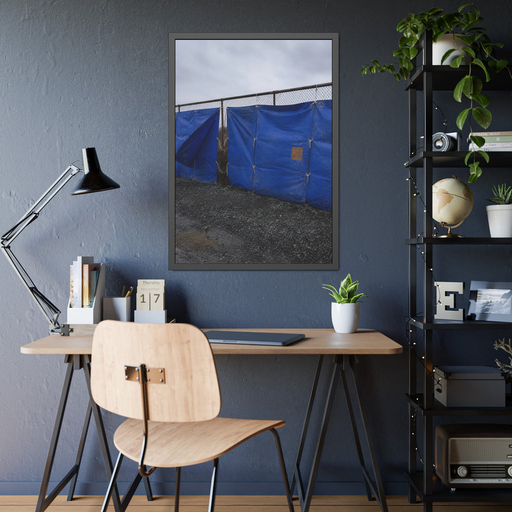 Blue tarps lashed to a chain link fence above gravel under grey sky. Drapery on the Fence by Garabaggio, framed fine art print hanging in a room.