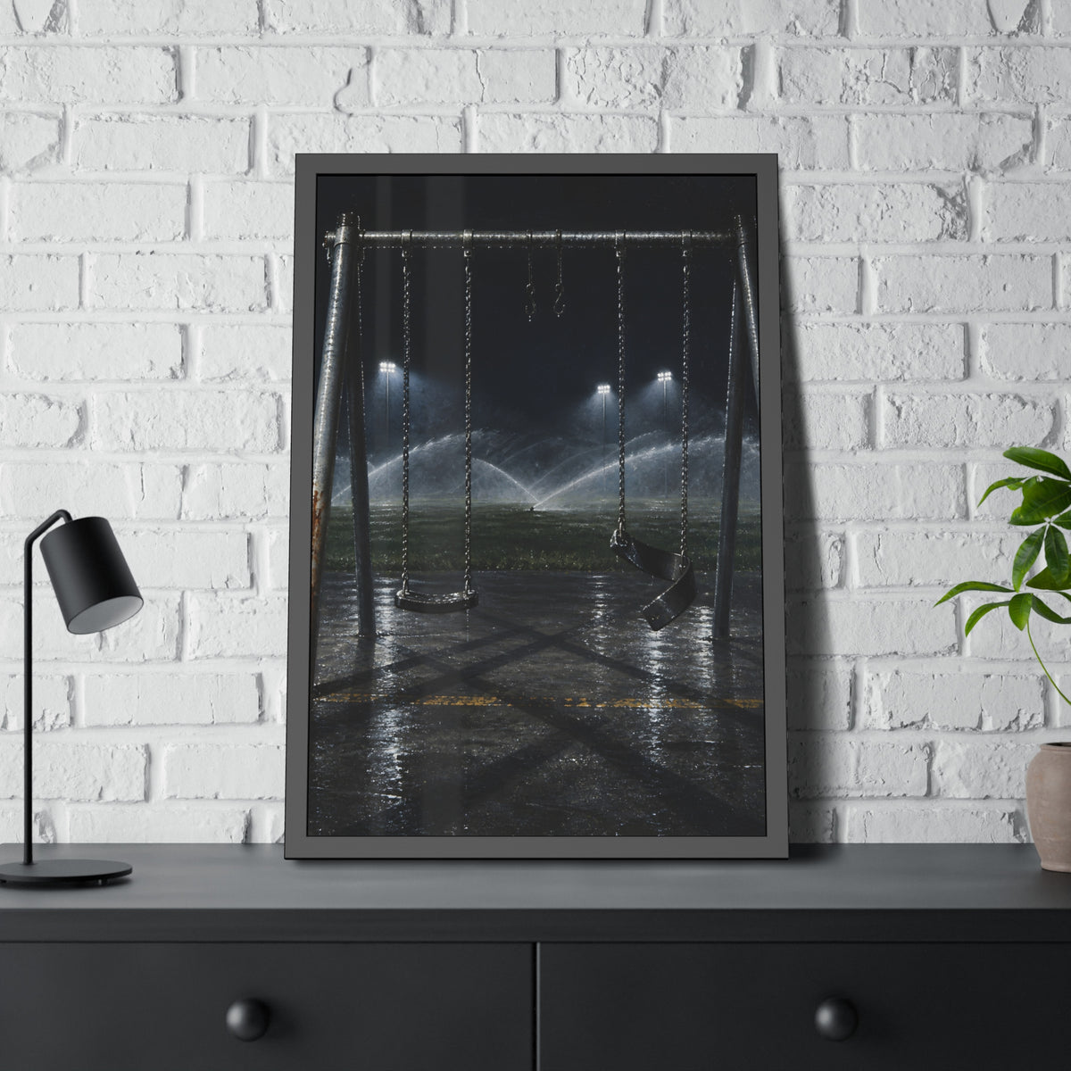 An empty swing set on wet asphalt, sprinklers arcing over the field. The Eleventh Hour: The Sprinklers by Garabaggio, framed fine art print hanging in a room.