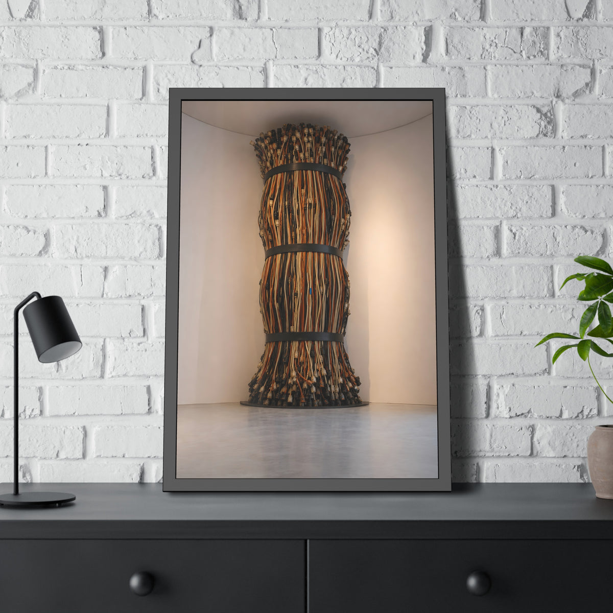 A tall column of bundled cords strapped in three places in a gallery corner. The Bundled Apse by Garabaggio, framed fine art print hanging in a room.