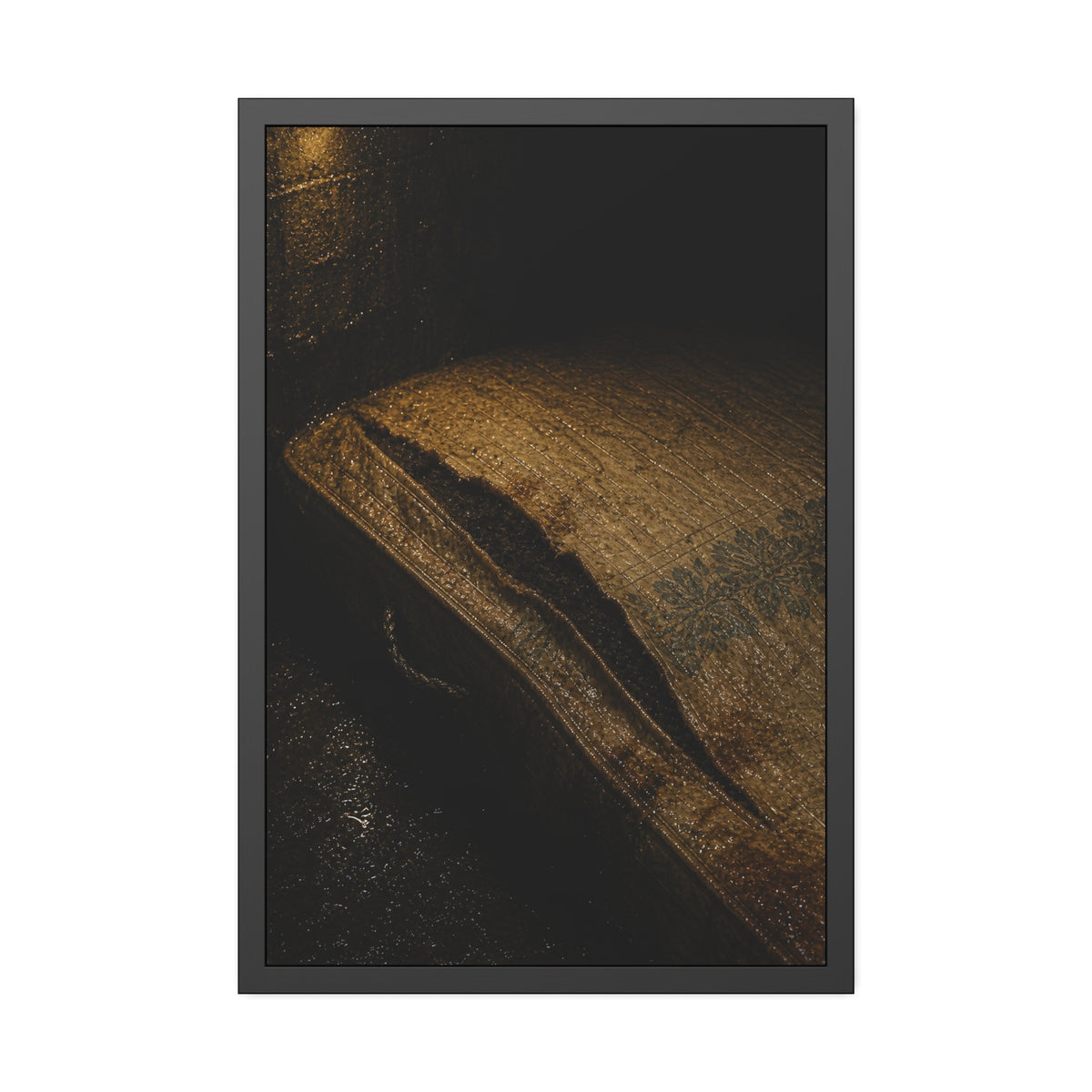 A mattress with its seam split open, lit warm against a dark wall. The Opening of the Ticking by Garabaggio, framed fine art print, 24″ x 36″.