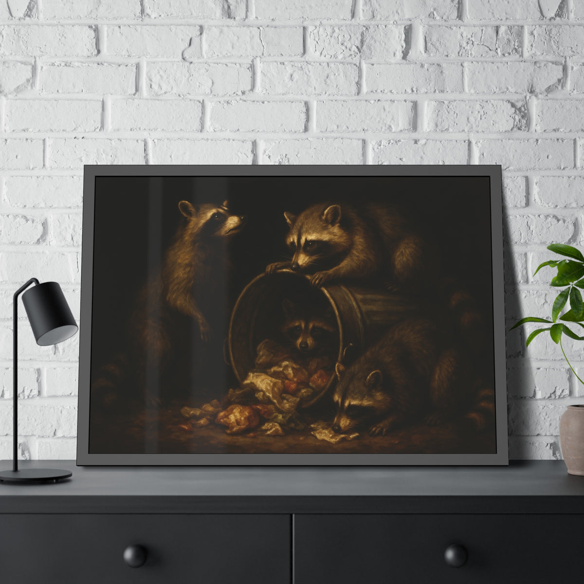 Four raccoons around a tipped metal trash can spilling food scraps. The Crowning with Crumbs by Garabaggio, framed fine art print hanging in a room.