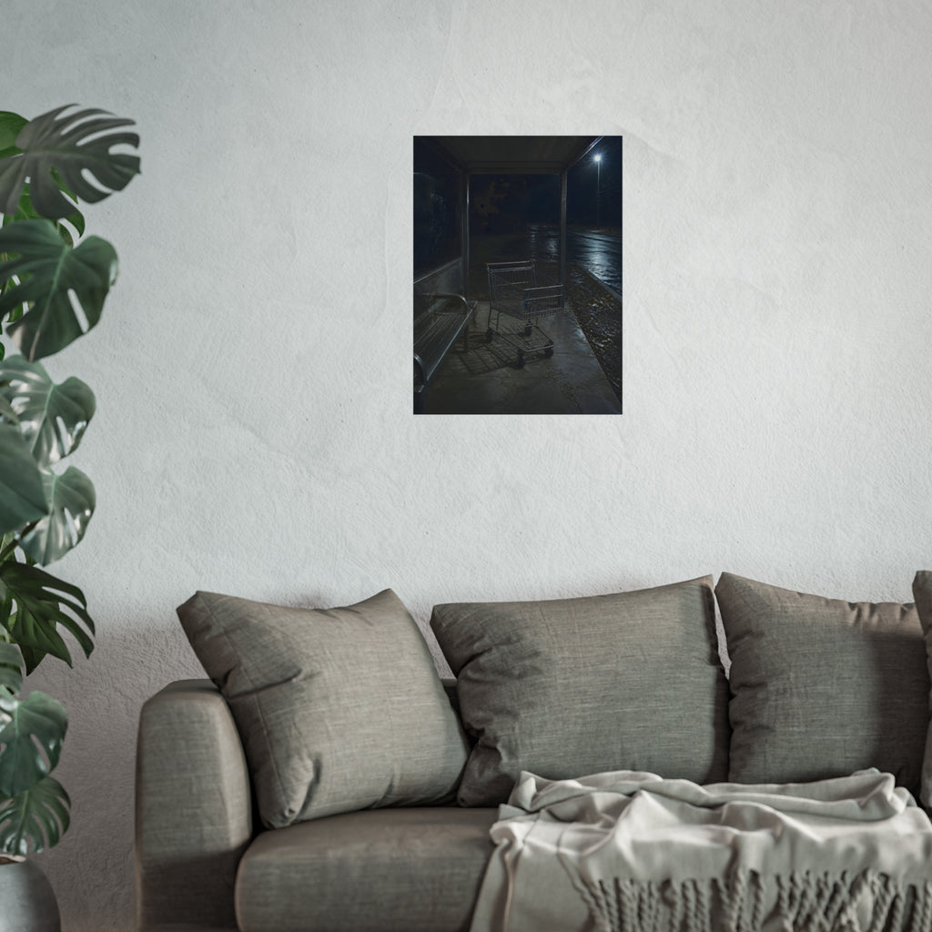 A shopping cart parked inside a bus shelter under a street lamp at night. The Rest at the Bus Shelter by Garabaggio, fine art print hanging in a room.