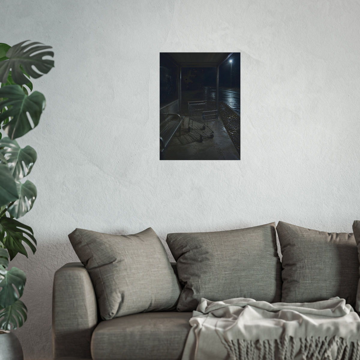 A shopping cart parked inside a bus shelter under a street lamp at night. The Rest at the Bus Shelter by Garabaggio, fine art print hanging in a room.