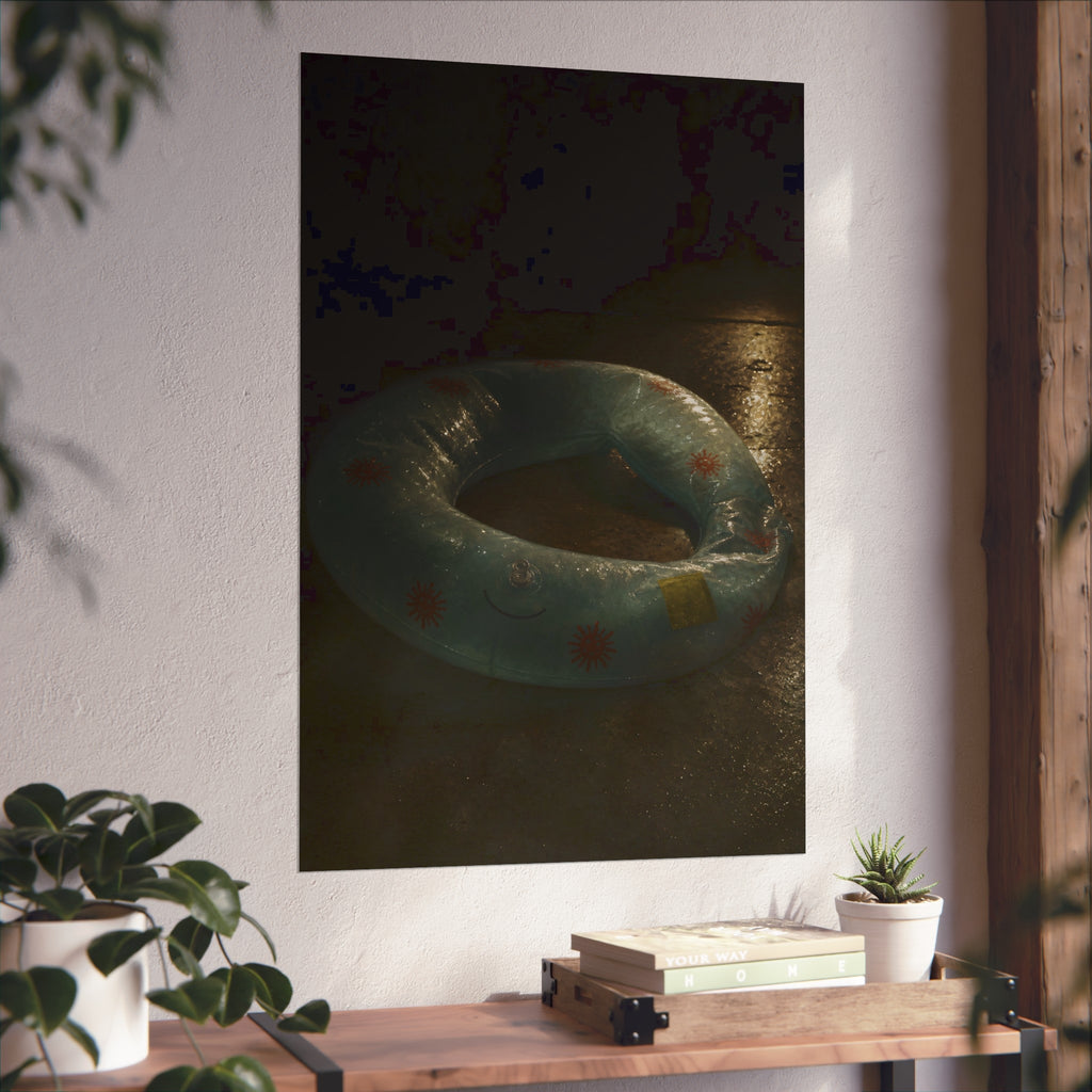 Deflated pool float ring on wet ground, lit from one side in the dark. After the Last Swim by Garabaggio, fine art print hanging in a room.