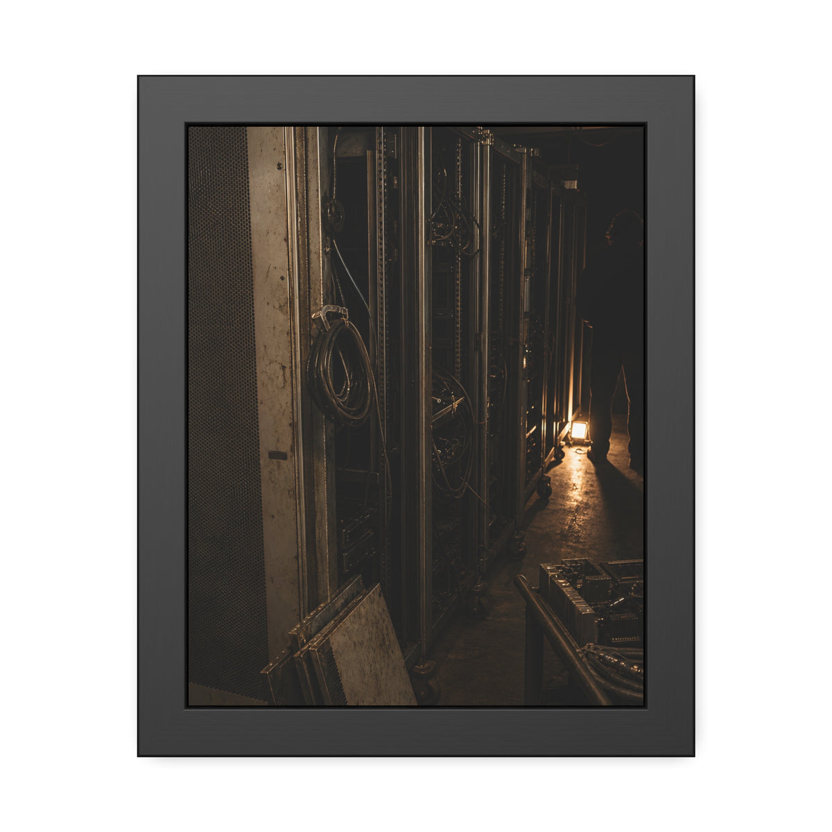 Open server racks in a dark room, a work lamp and a figure at the end. Garabaggio at the End of the Row by Garabaggio, framed fine art print, 11″ x 14″.
