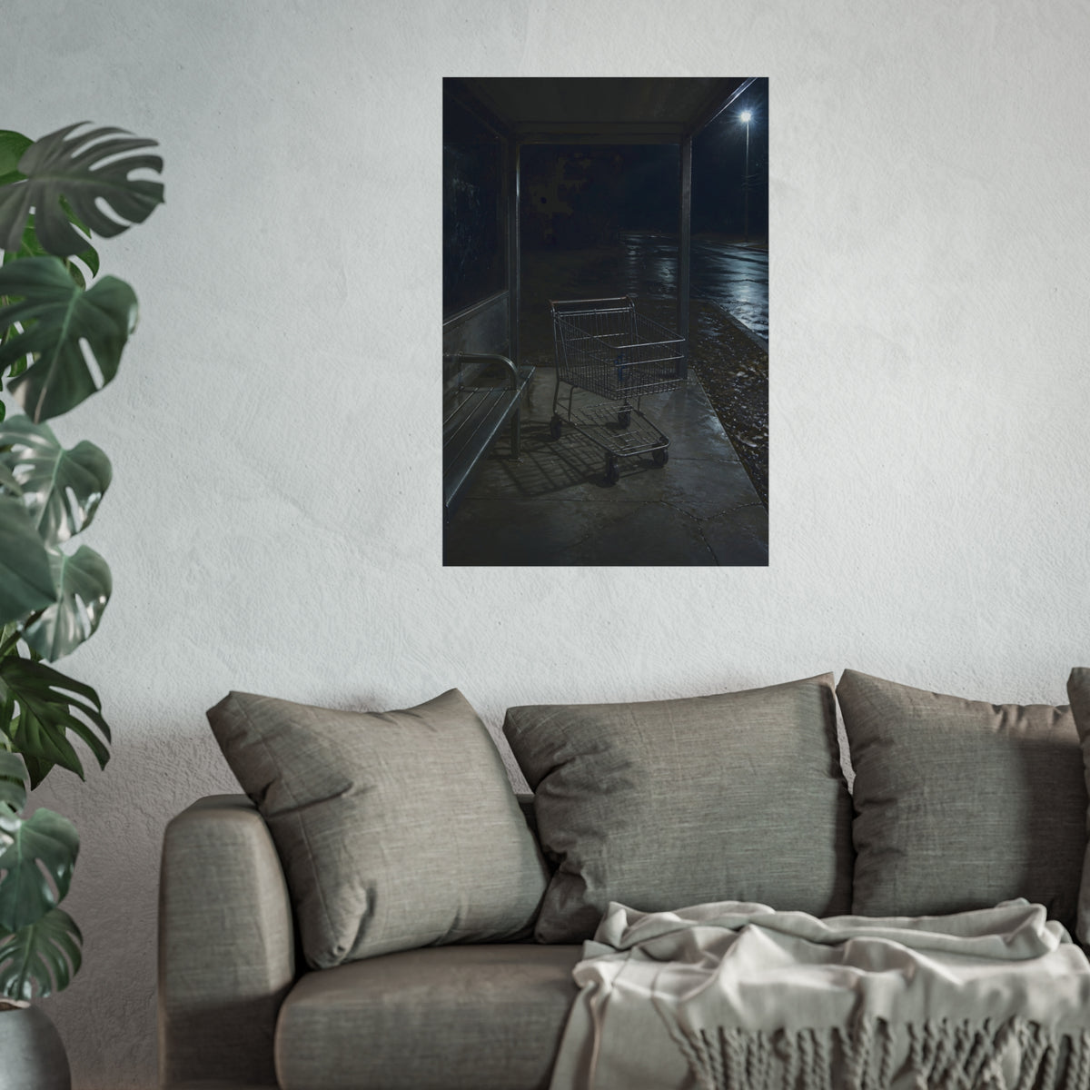 A shopping cart parked inside a bus shelter under a street lamp at night. The Rest at the Bus Shelter by Garabaggio, fine art print hanging in a room.