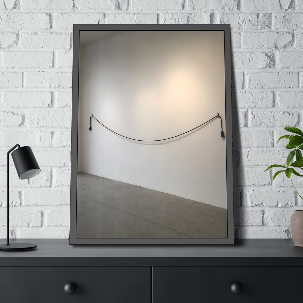 An extension cord hung in a long slack curve across a bare white wall. The Unplugged Line by Garabaggio, framed fine art print hanging in a room.