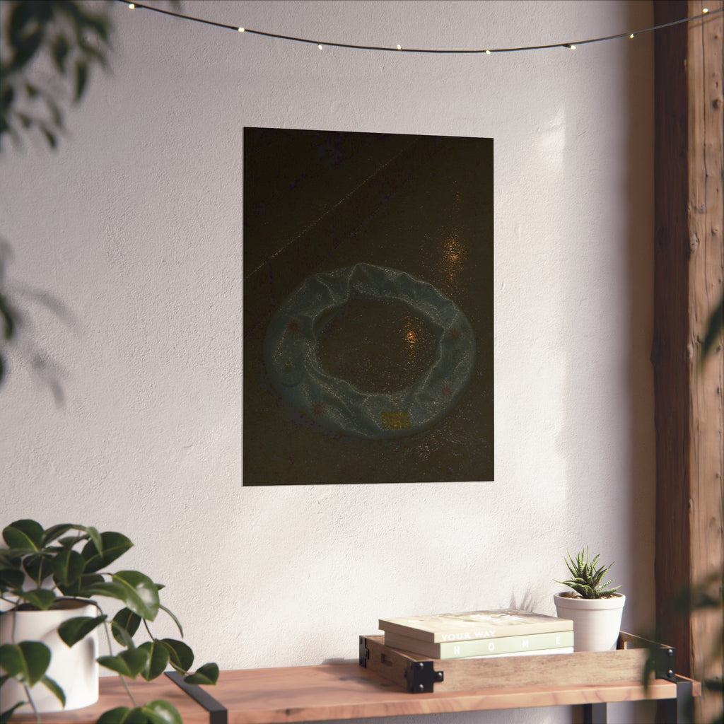 A deflated ring float holding rainwater on wet pavement at night. The Basin of Rain (Pool Float) by Garabaggio, fine art print hanging in a room.