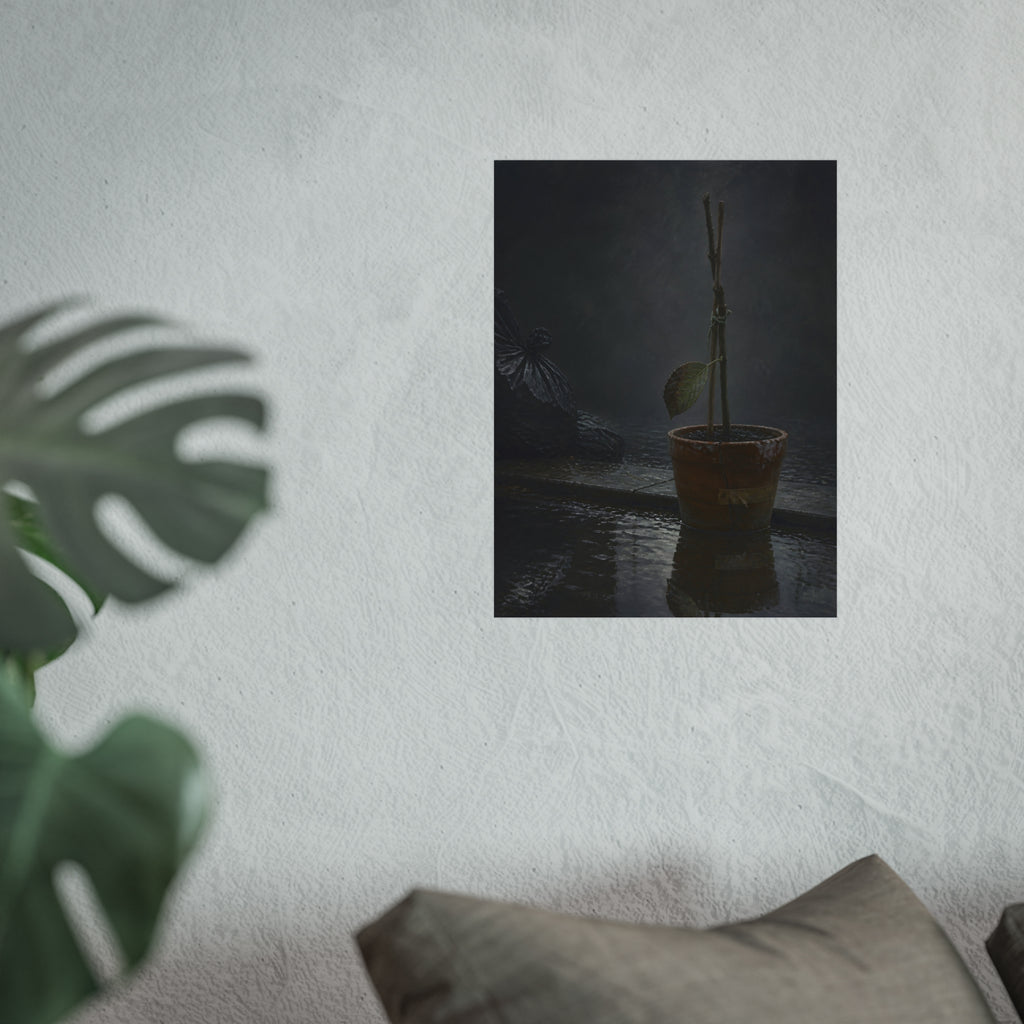 Bare tied stems in a clay pot on flooded pavement, one leaf remaining. The Grey Between by Garabaggio, fine art print hanging in a room.