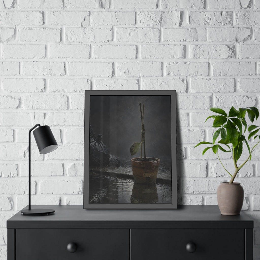 Bare tied stems in a clay pot on flooded pavement, one leaf remaining. The Grey Between by Garabaggio, framed fine art print hanging in a room.