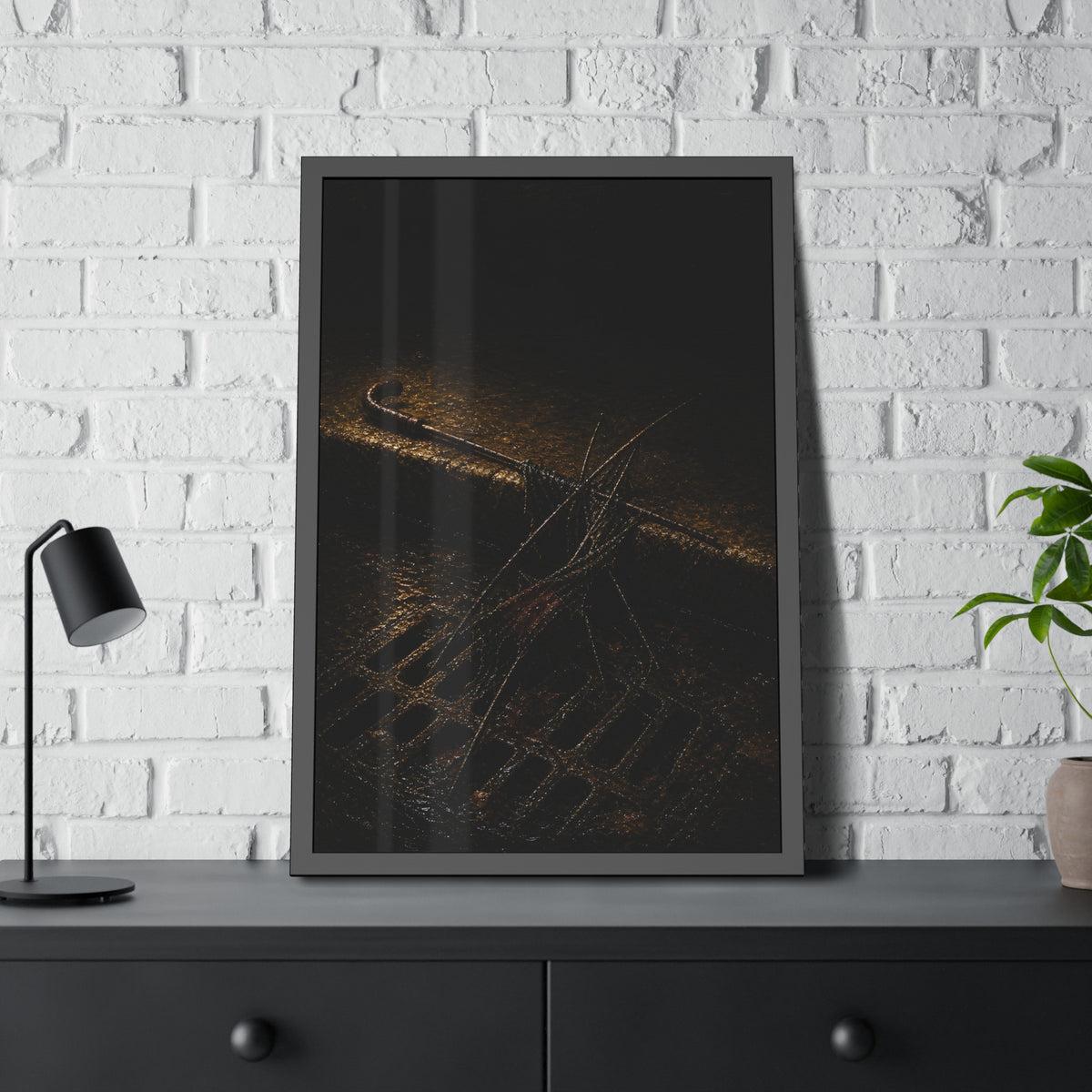 A broken umbrella collapsed across a storm drain grate at the curb. The Burial at the Storm Drain by Garabaggio, framed fine art print hanging in a room.
