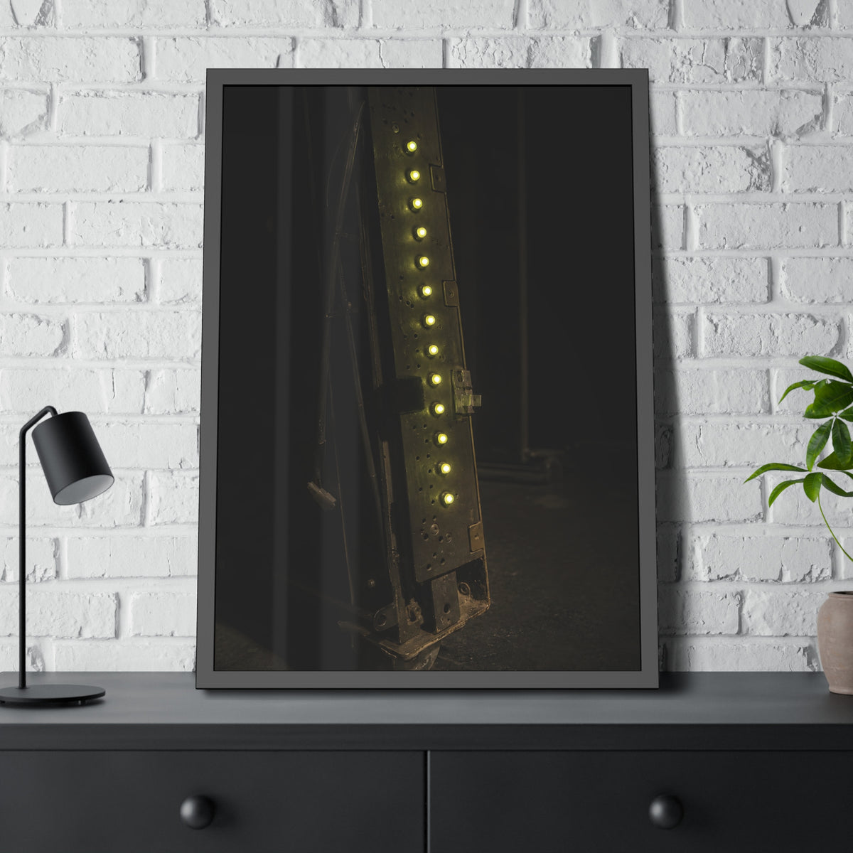 A dark rack panel with a vertical row of glowing green indicator lights. The First Green Choir by Garabaggio, framed fine art print hanging in a room.