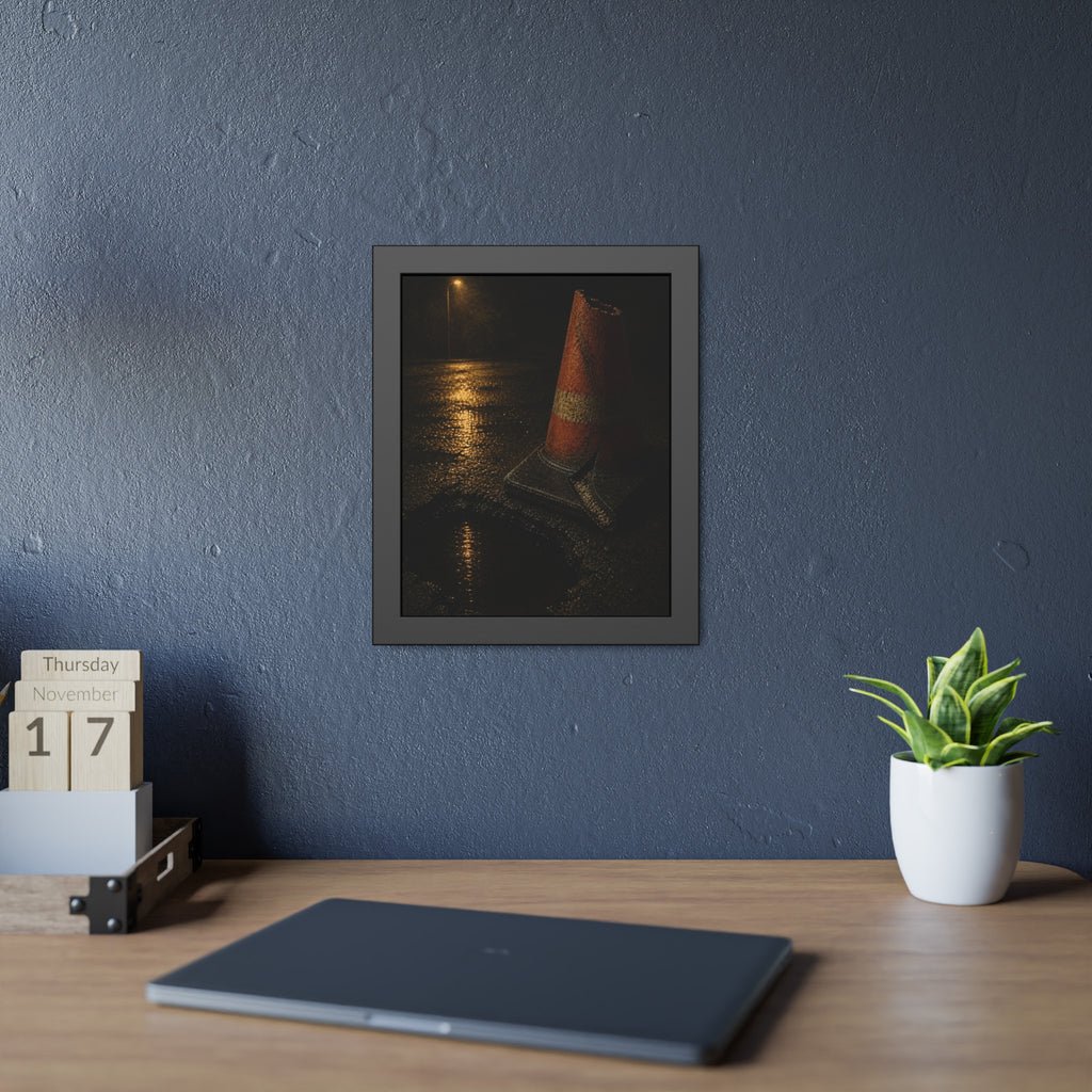 A traffic cone beside a water filled pothole reflecting a street lamp. The Sentinel of the Pothole by Garabaggio, framed fine art print hanging in a room.