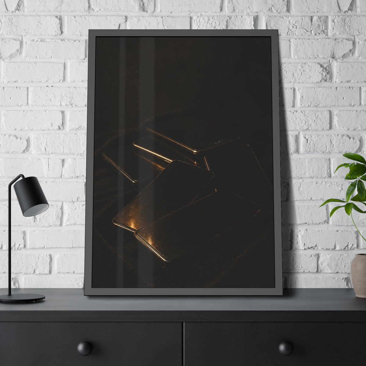 Stack of dead phone screens on dark cloth, edges catching warm light. After the Light Goes Out by Garabaggio, framed fine art print hanging in a room.