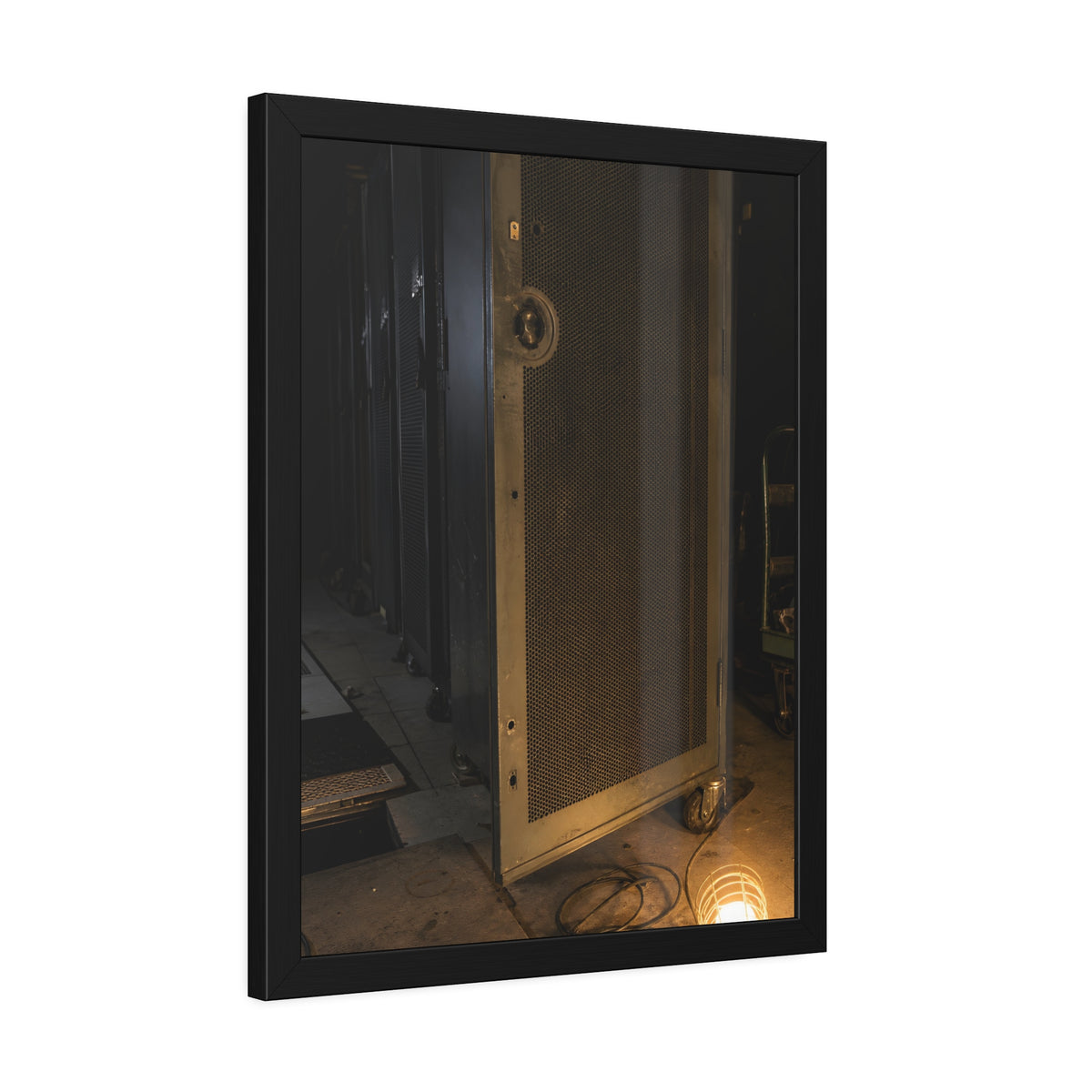 A perforated server rack door in a dark aisle lit by a floor work lamp. The Cold Aisle by Garabaggio, framed fine art print hanging in a room.