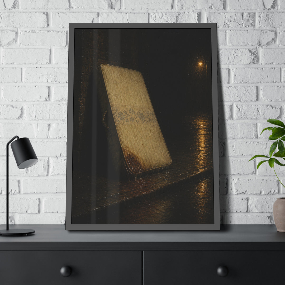 A stained mattress leaning against a wall in rain under a streetlamp. The First Rain by Garabaggio, framed fine art print hanging in a room.
