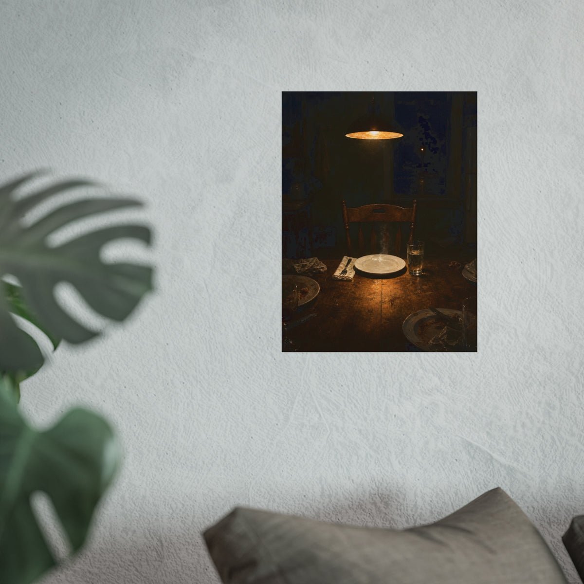 A clean plate and empty chair under a hanging lamp at a used dinner table. The Empty Seat at Dinner by Garabaggio, fine art print hanging in a room.