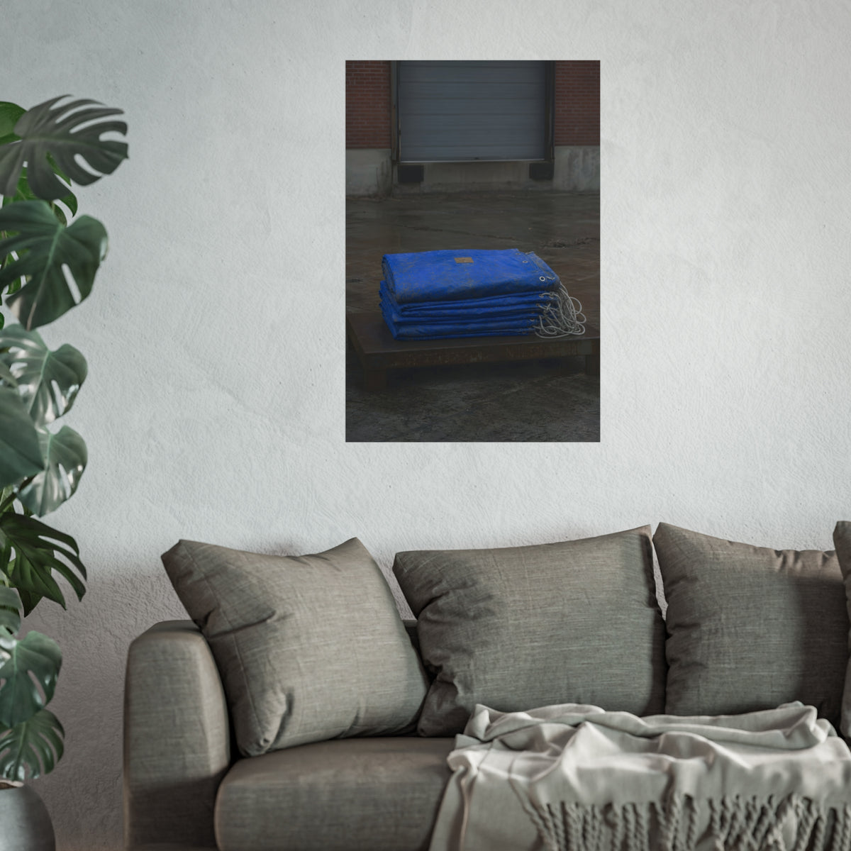 A folded blue tarp stacked on a low wooden platform by a loading dock. The Repaired Fold by Garabaggio, fine art print hanging in a room.