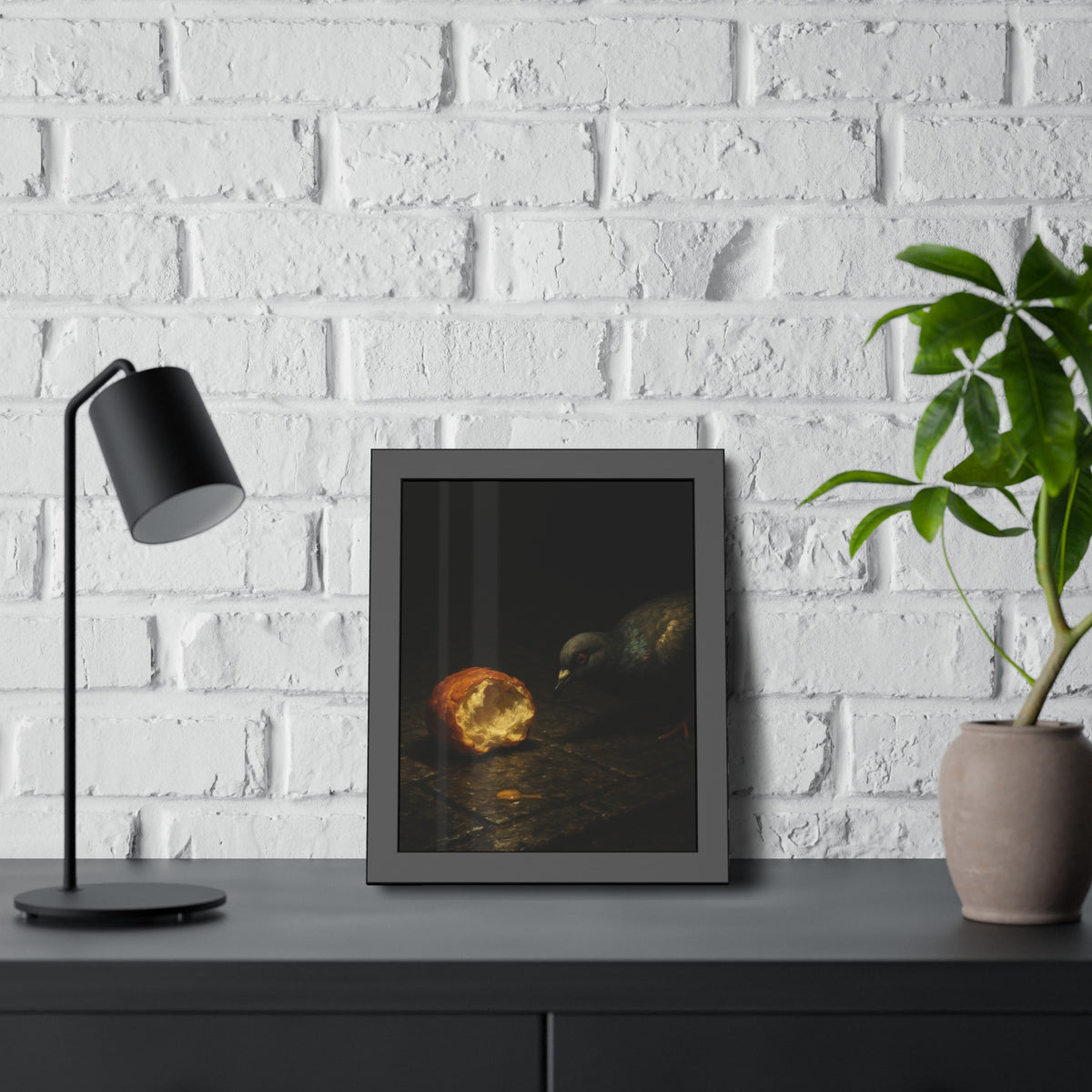 A pigeon leaning toward a torn bread roll on wet paving stones. The Offering of the Discarded Bun by Garabaggio, framed fine art print hanging in a room.