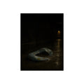 A deflated pool float ring on wet alley pavement, a lit doorway far behind. The Crossing of the Alley by Garabaggio, fine art print, 12″ x 16″.