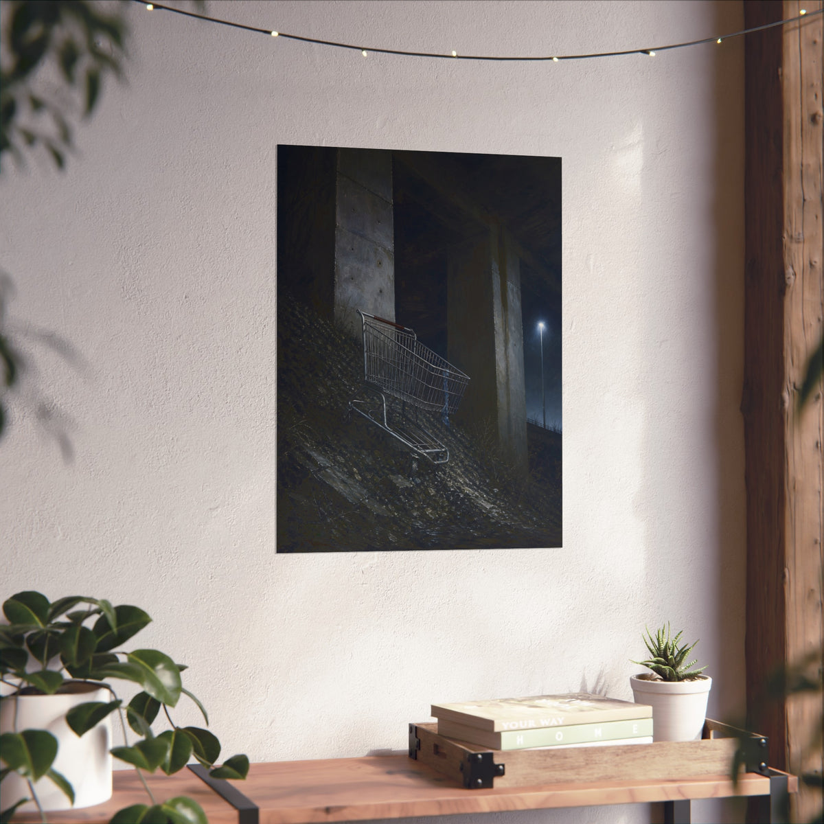A shopping cart on a rocky slope under an overpass near a streetlamp. The Descent to the Underpass by Garabaggio, fine art print hanging in a room.