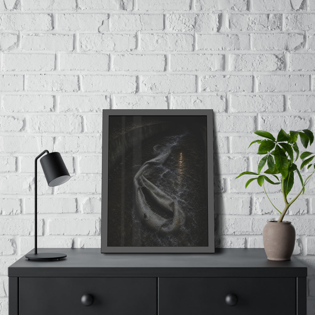A deflated pool float caught in a concrete drainage channel of running water. The Release into Runoff by Garabaggio, framed fine art print hanging in a room.