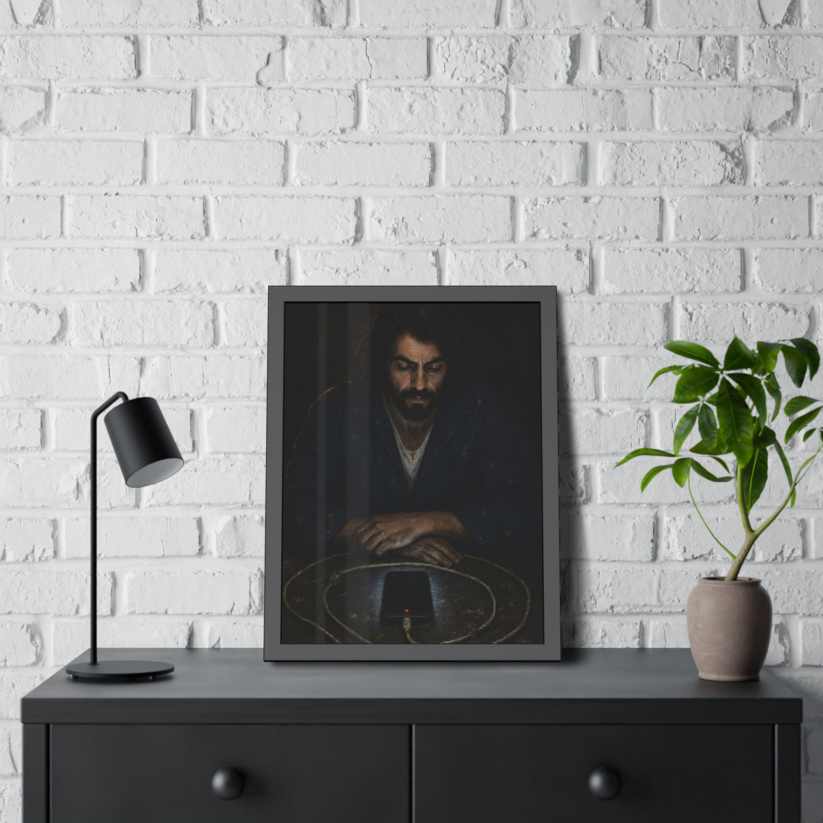 A bearded man at a table watching a phone charging inside a coiled cable. The Vigil of the Charging Cord by Garabaggio, framed fine art print hanging in a room.