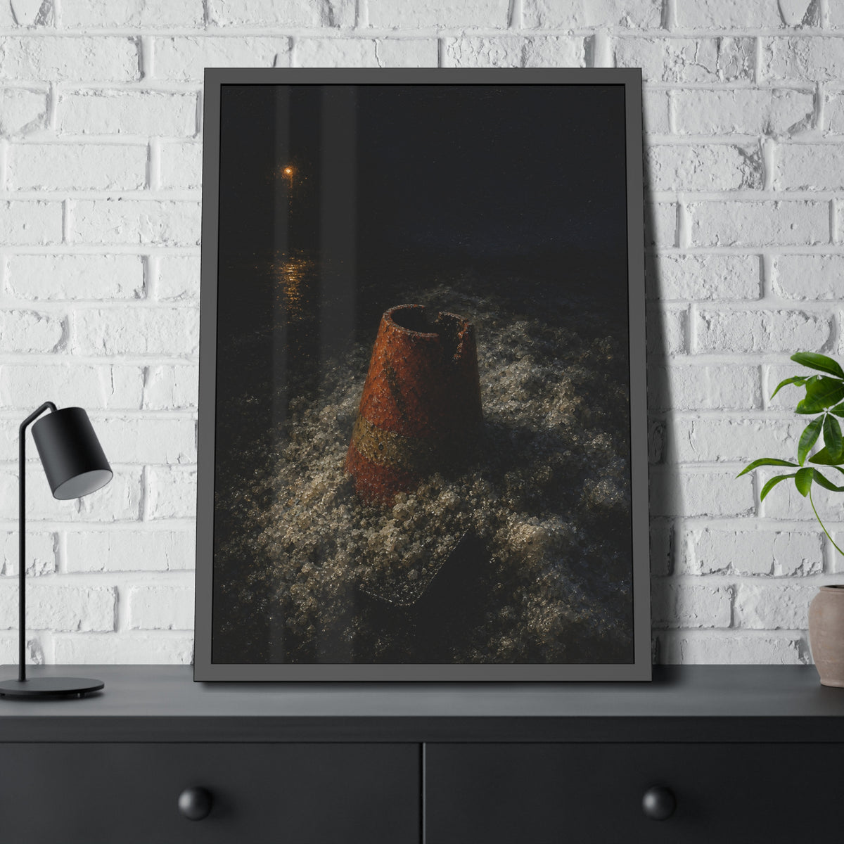 An orange traffic cone half buried in road salt under a distant streetlight. The Burial in Road Salt by Garabaggio, framed fine art print hanging in a room.