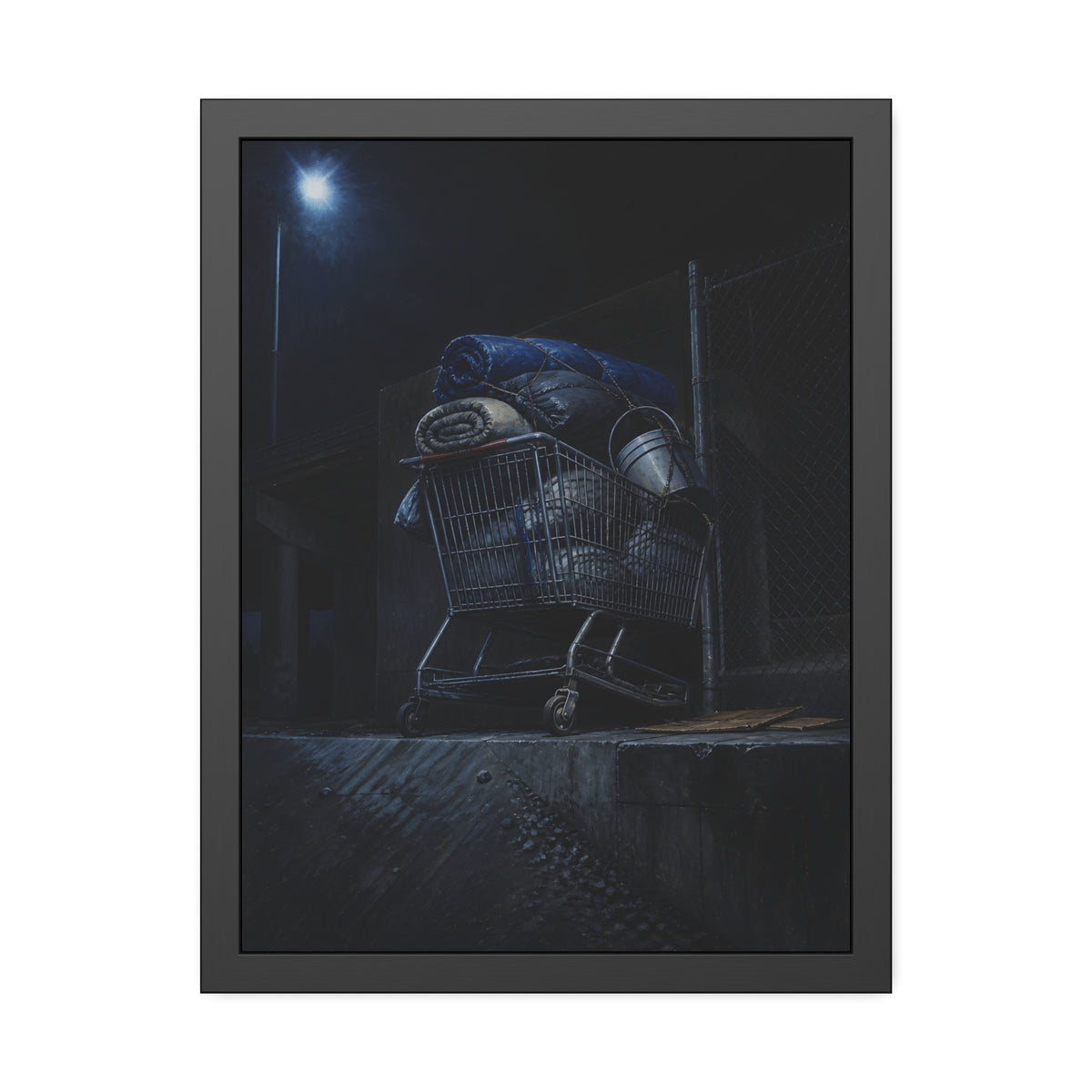 A shopping cart piled with bedding and buckets under a streetlamp. The Loading of Another Life by Garabaggio, framed fine art print, 18″ x 24″.