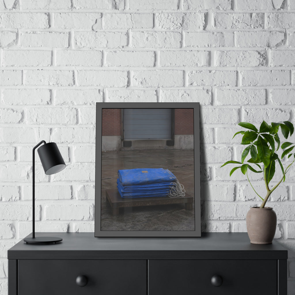 A folded blue tarp stacked on a low wooden platform by a loading dock. The Repaired Fold by Garabaggio, framed fine art print hanging in a room.