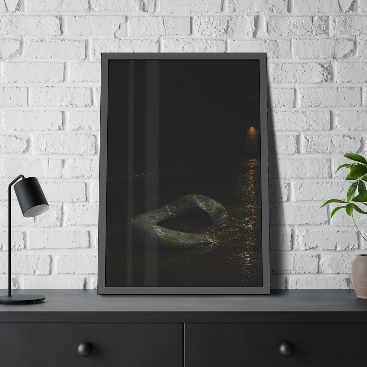 A deflated pool float ring on wet alley pavement, a lit doorway far behind. The Crossing of the Alley by Garabaggio, framed fine art print hanging in a room.
