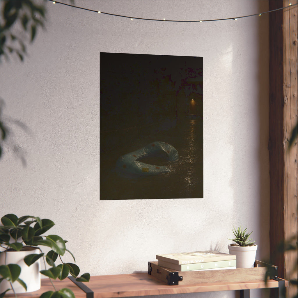 A deflated pool float ring on wet alley pavement, a lit doorway far behind. The Crossing of the Alley by Garabaggio, fine art print hanging in a room.