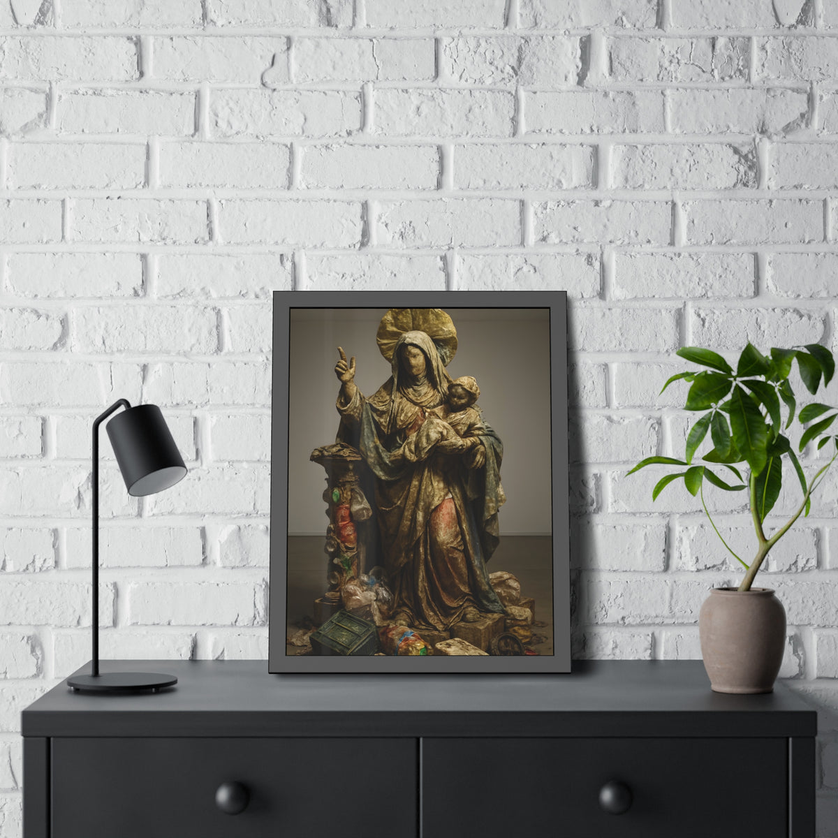 A standing veiled figure holding a child, refuse piled around the base. The Virgin of the Landfill by Garabaggio, framed fine art print hanging in a room.