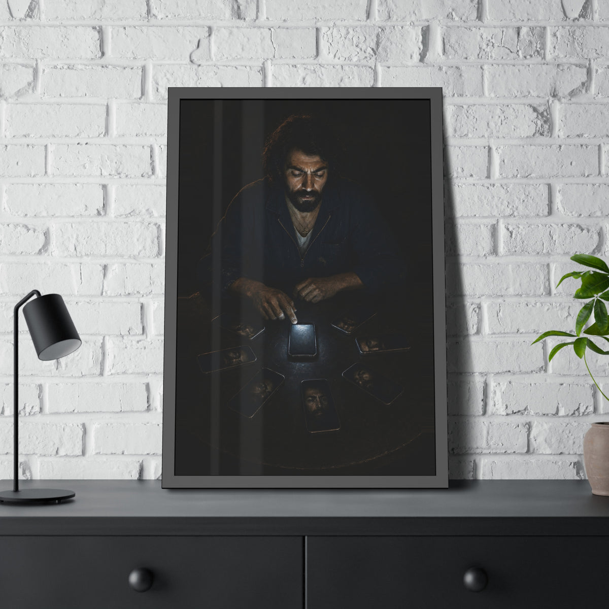 A bearded man at a dark table ringed by phones, one lit screen under his hand. The Congregation of Faces by Garabaggio, framed fine art print hanging in a room.